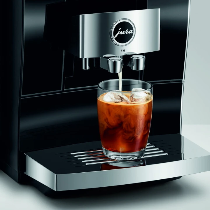 Ekspres Jura Z10 w kolorze Diamond Black - błyszczącej czerni, zaprezentowany ze szklanką kawy Cold-brew