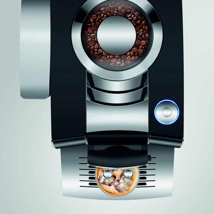 Ekspres Jura Z10 w kolorze Diamond Black - błyszczącej czerni, zaprezentowany od góry, z widokiem na zbiornik ziaren oraz rotary switch, ze szklanką kawy Cold-brew