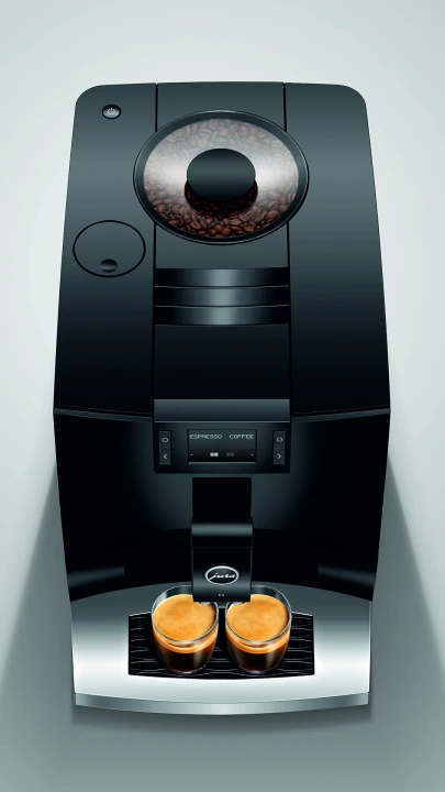Ekspres Jura C3 EA w kolorze Piano Black, zaprezentowany od góry, z widokiem na zbiornik ziaren kawy, z dwiema szklankami espresso