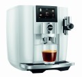 Ekspres Jura J8 w kolorze Piano White, zaprezentowany od lewej strony, z widokiem na zbiornik wody, ze szklanką kawy czarnej
